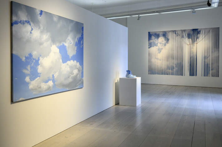 Blick in die Ausstellung Ein heller Raum mit verschiedenen Bildern und Skulpturen von Wolken