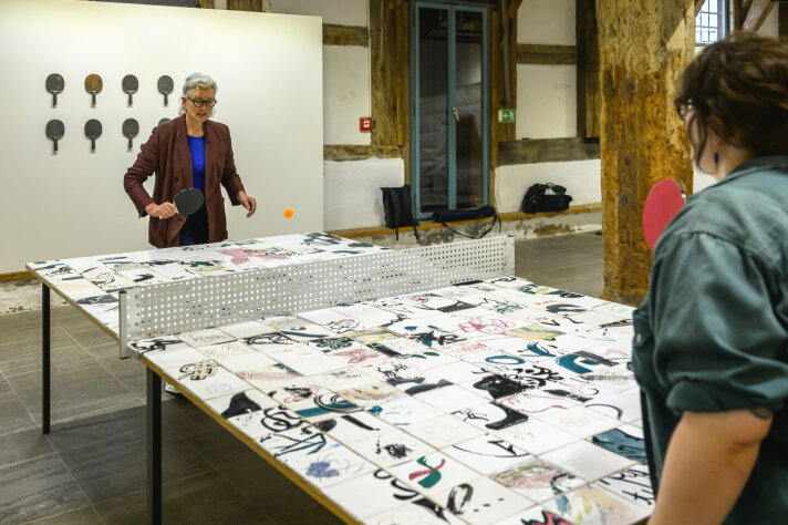 Prof. Dr. Elke Werner, Direktorin der Kunstmuseen, testet mit einer Besucherin die Tischtennisplatte von Künstlerin Josephine Schulz Zwei Frauen spielen Tischtennis an einer bunten Platte in einem Raum stehend
